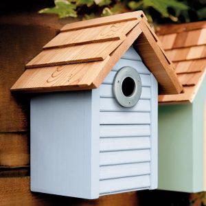 Blue Bird nesting box with brown roof hanging on brown fence