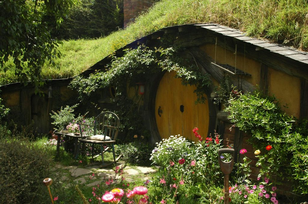 A picture of a garden with chair and bench in front of a circular door on The Hobbiton Movie set